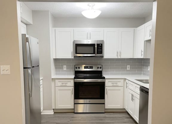 a kitchen with stainless steel appliances and white cabinets at Madison Oaks Apartment Homes, LLC, Palm Harbor, FL