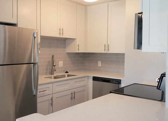a kitchen with white cabinets and a stainless steel refrigerator at Madison Oaks Apartment Homes, LLC, Palm Harbor
