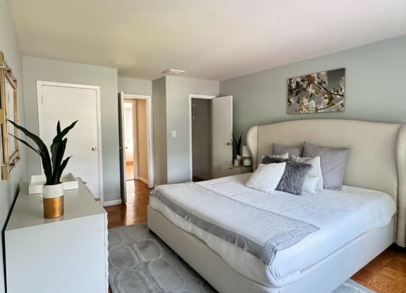 a bedroom with a large bed and a white dresser at Raritan Crossing Apartment Homes, New Brunswick, NJ 08901