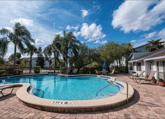 a swimming pool with chairs and a house in the background at Sunscape Apartment Homes, Tampa, 33613