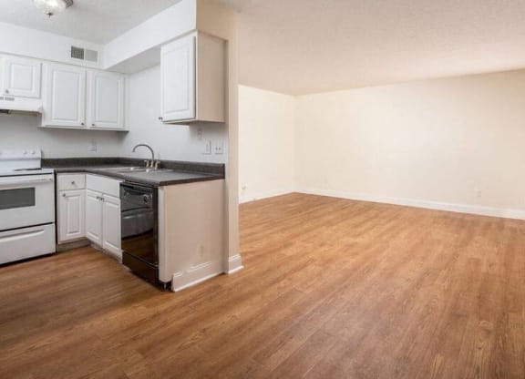 an empty kitchen with white cabinets and a wood floor  at Oak Manor Apartment Homes, Tampa, Florida