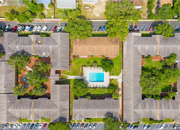 An aerial view of a parking lot with a swimming pool in the middle.