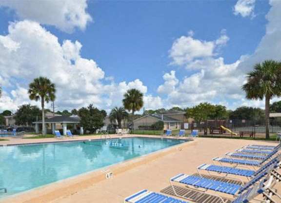 A pool with blue lounge chairs and palm trees in the background.