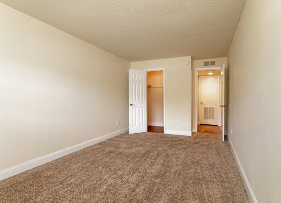 A room with carpeted floor and two doors.