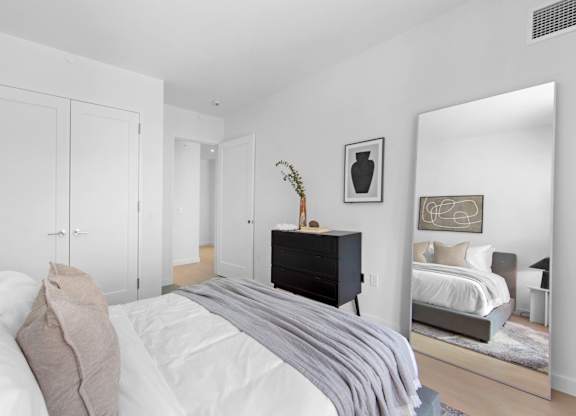 A bedroom with a bed, a dresser, and a mirror.