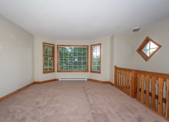 a large room with a carpeted floor and three windows
