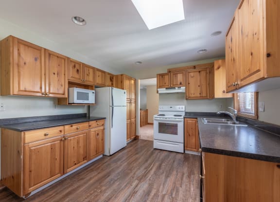 a kitchen with wood cabinets and black countertops