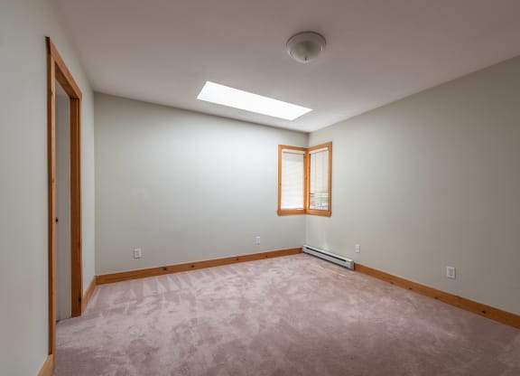 an empty room with a skylight and a wooden door