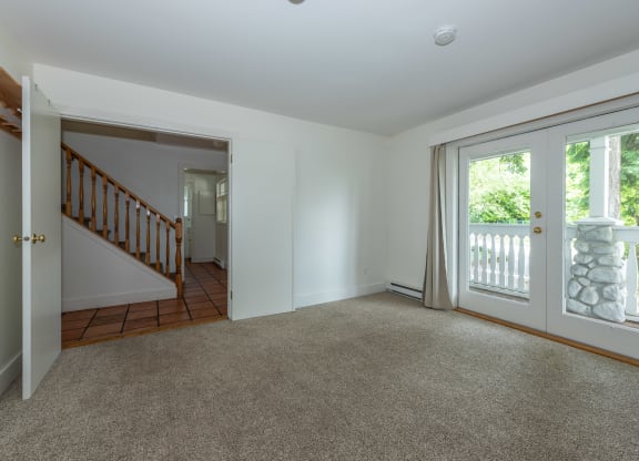 a bedroom with a sliding glass door and a staircase in the background