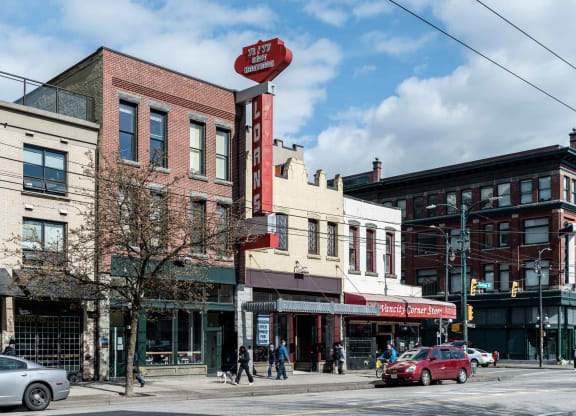 a view of a street corner with people walking and cars parked on the side of the road