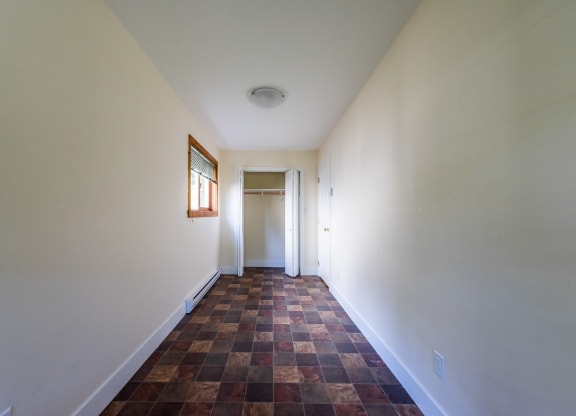 a corridor in a house with white walls and a brown tile floor