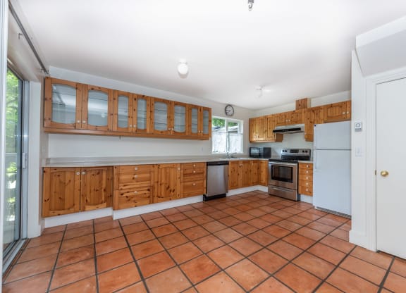 a kitchen with wooden cabinets and a tiled floor