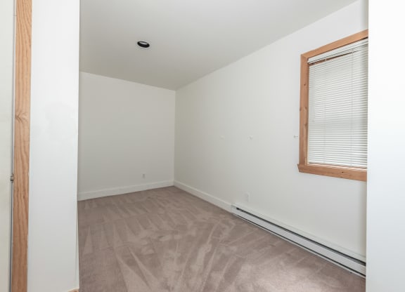 a bedroom with white walls and a wooden floor