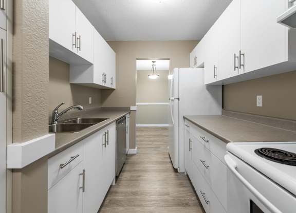 A kitchen with white cabinets and a stove top oven.