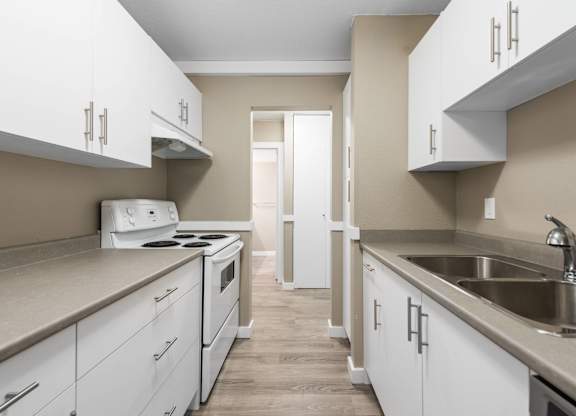 A kitchen with white cabinets and a stove top oven.