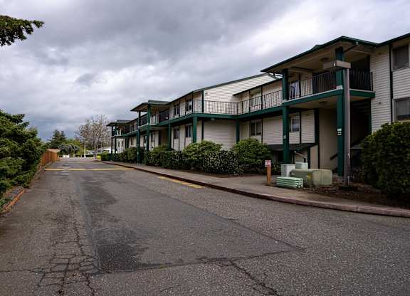 A street view of apartment buildings with a cloudy sky.