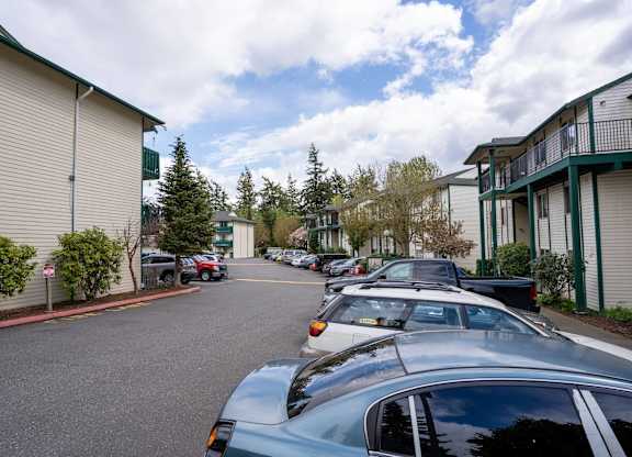 A parking lot with cars parked in front of apartment buildings.