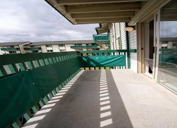 A balcony with a green railing and a concrete floor.