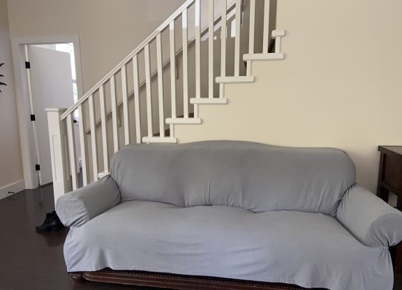 a couch in a living room with a staircase in the background