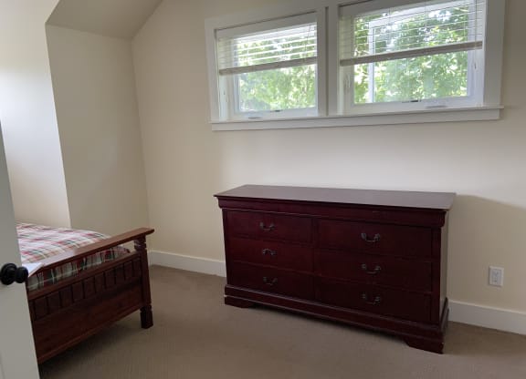 a bedroom with a dresser and two windows