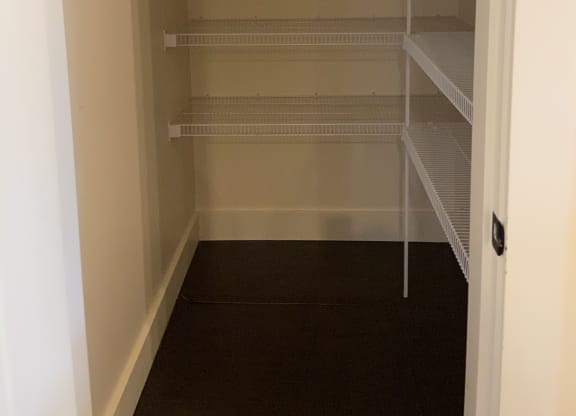 a walk in closet with white walls and a white floor