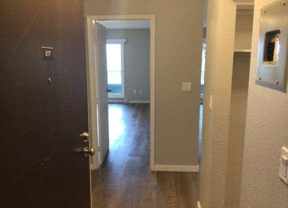 an open door leading to a hallway with a door open and a window in the background