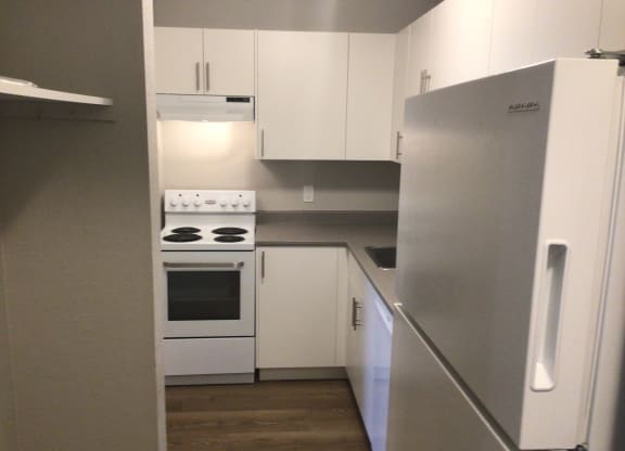 a small kitchen with white cabinets and a white stove