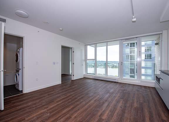 an empty living room with hardwood floors and large windows