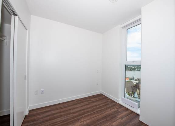 a bedroom with a large window and hardwood floors