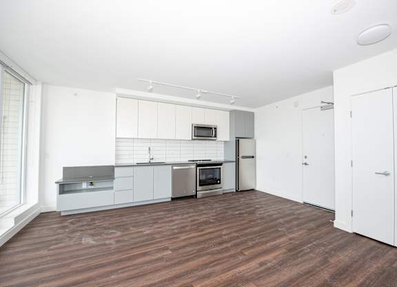 a bedroom with a medium sized white wardrobe and a kitchen with white cabinets and stainless steel appliances