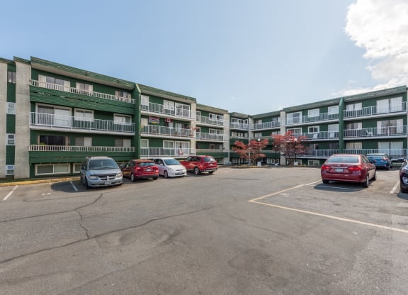 a large parking lot with cars in front of an apartment building