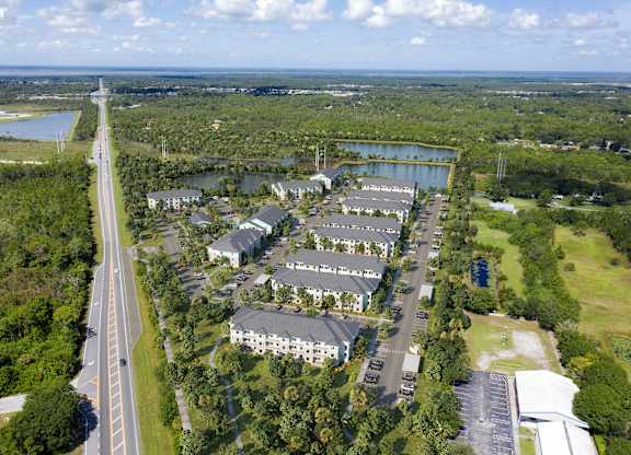 A bird's eye view of a highway running through a residential area with a large building on the right. at Allegra at Cocoa in Cocoa, FL, 32926