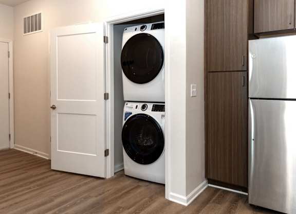 A white door is open to reveal a black washing machine inside.