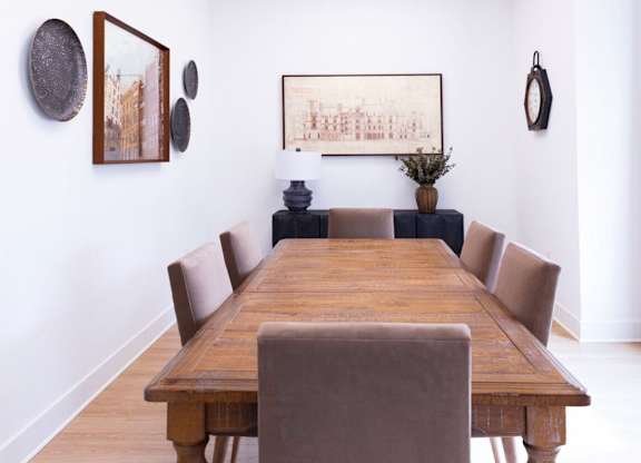 A long wooden table with chairs and pictures on the wall.