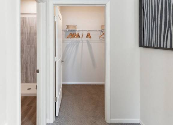 A white closet with clothes hanging on a rack.