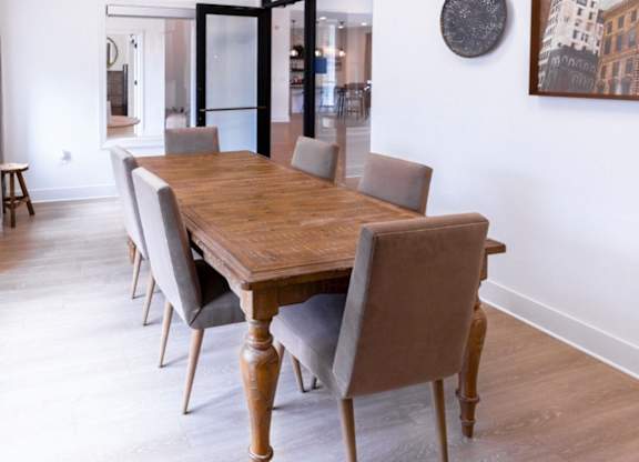 A long wooden table with grey chairs in a room.