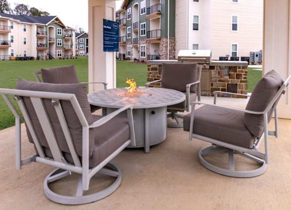A patio with a table and chairs and a sign in the background.