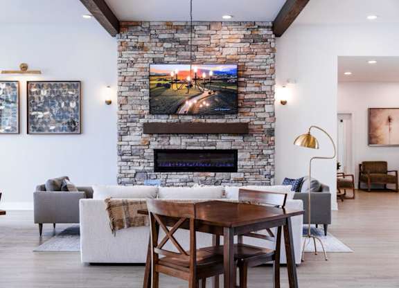 A modern living room with a stone fireplace and a television mounted above it.