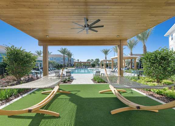 A wooden pergola with a ceiling fan is over a green lawn with two hammocks.at Allegra at Cocoa in Cocoa, FL, 32926