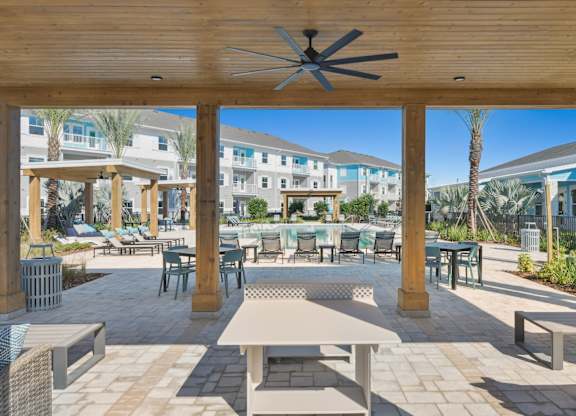 A patio with a table and chairs under a roof.at Allegra at Cocoa in Cocoa, FL, 32926