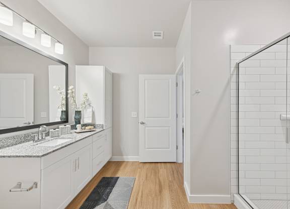 A bathroom with a white tile shower and a white sink.at Allegra at Cocoa in Cocoa, FL, 32926