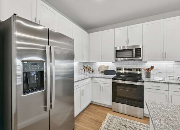A modern kitchen with a stainless steel refrigerator and white cabinets.at Allegra at Cocoa in Cocoa, FL, 32926