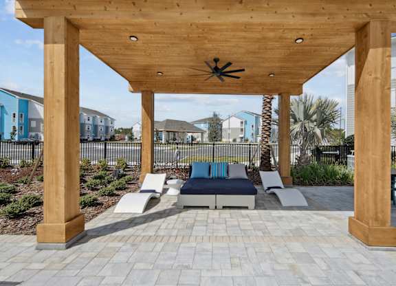 A wooden pergola with a ceiling fan is over a patio with cushioned seating. at Allegra at Cocoa in Cocoa, FL, 32926