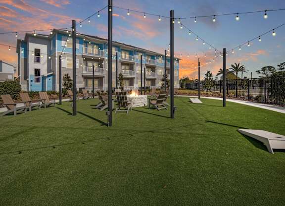 A sunset view of the grassy fire pit area with a Allegra at Cocoa Apartments in the background. at Allegra at Cocoa in Cocoa, FL, 32926