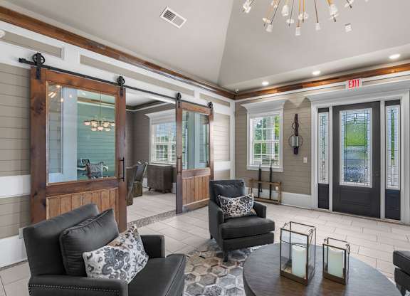 A living room with a black couch and a glass door.  at Mode at Melbourne Apartments, Melbourne, Florida
