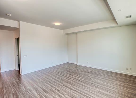an empty living room with wood flooring and white walls