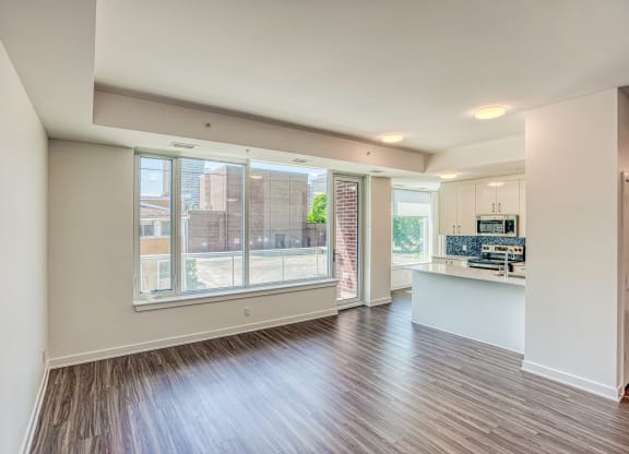an empty living room and kitchen with a large window