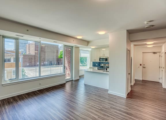 an empty living room with a large window and a kitchen