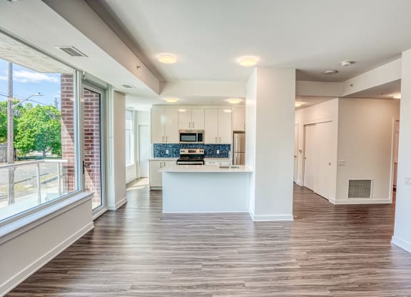 an empty living room and kitchen with a large window