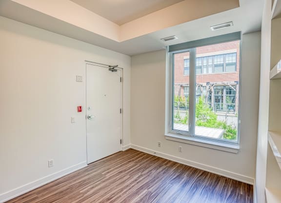 an empty room with a large window and wood flooring